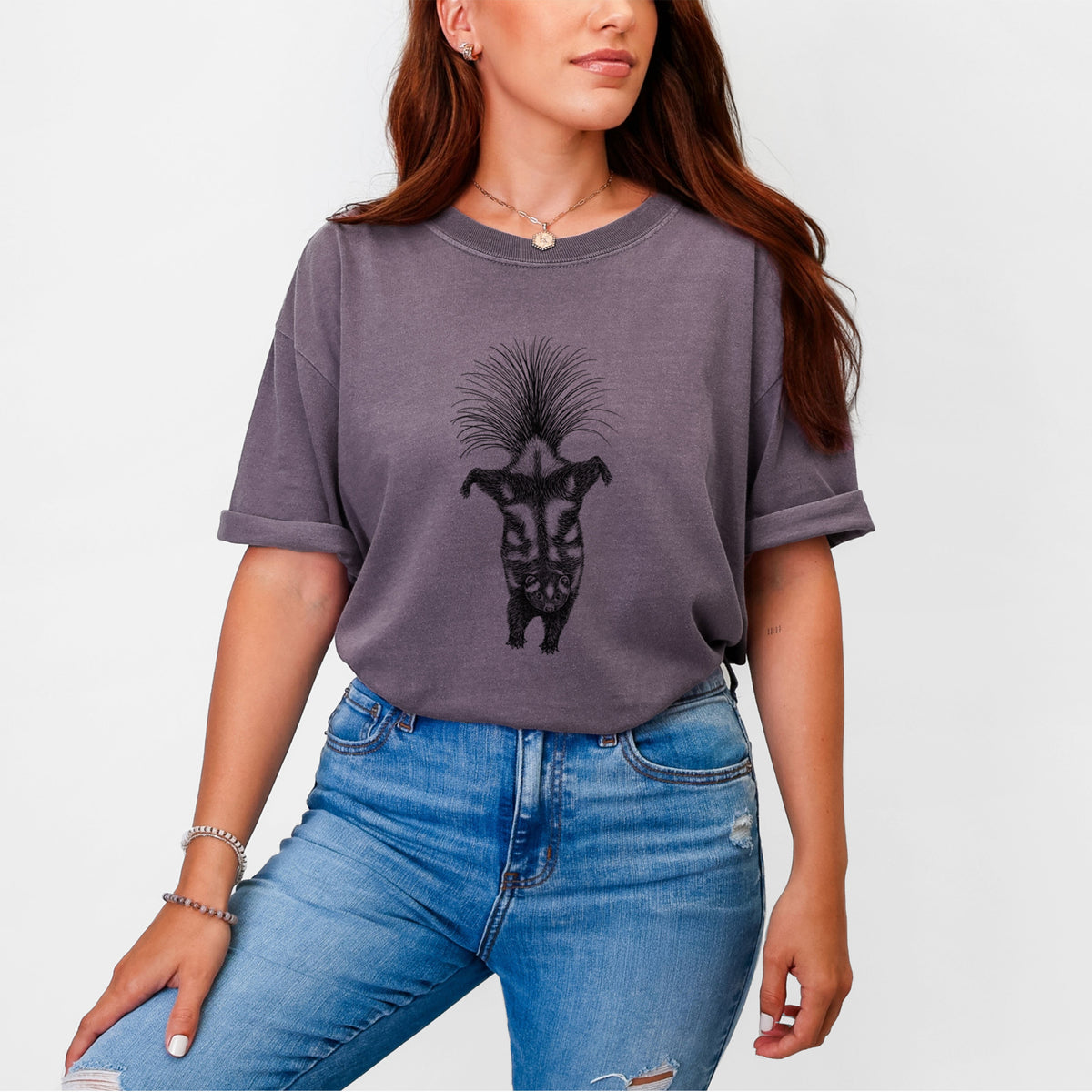 Woman wearing a Comfort Colors t-shirt printed with a black ink illustration of a spotted skunk doing a handstand with its tail fanned.