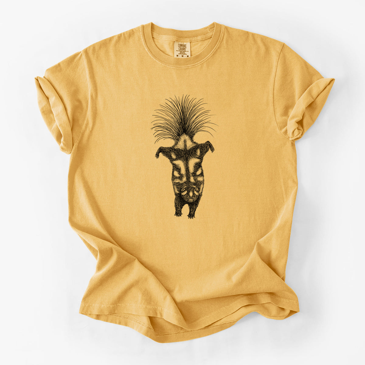 Golden wheat yellow Comfort Colors t-shirt laid flat, printed with a black ink illustration of a spotted skunk doing a handstand with its tail fanned.