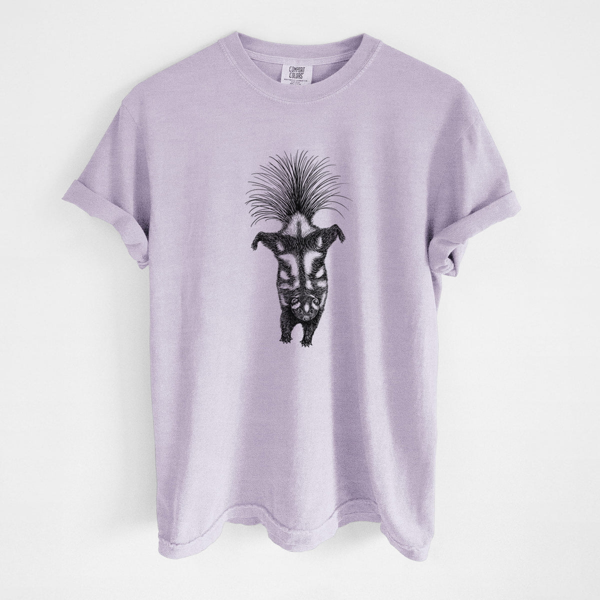 Orchid purple Comfort Colors t-shirt laid flat, printed with a black ink illustration of a spotted skunk doing a handstand with its tail fanned.