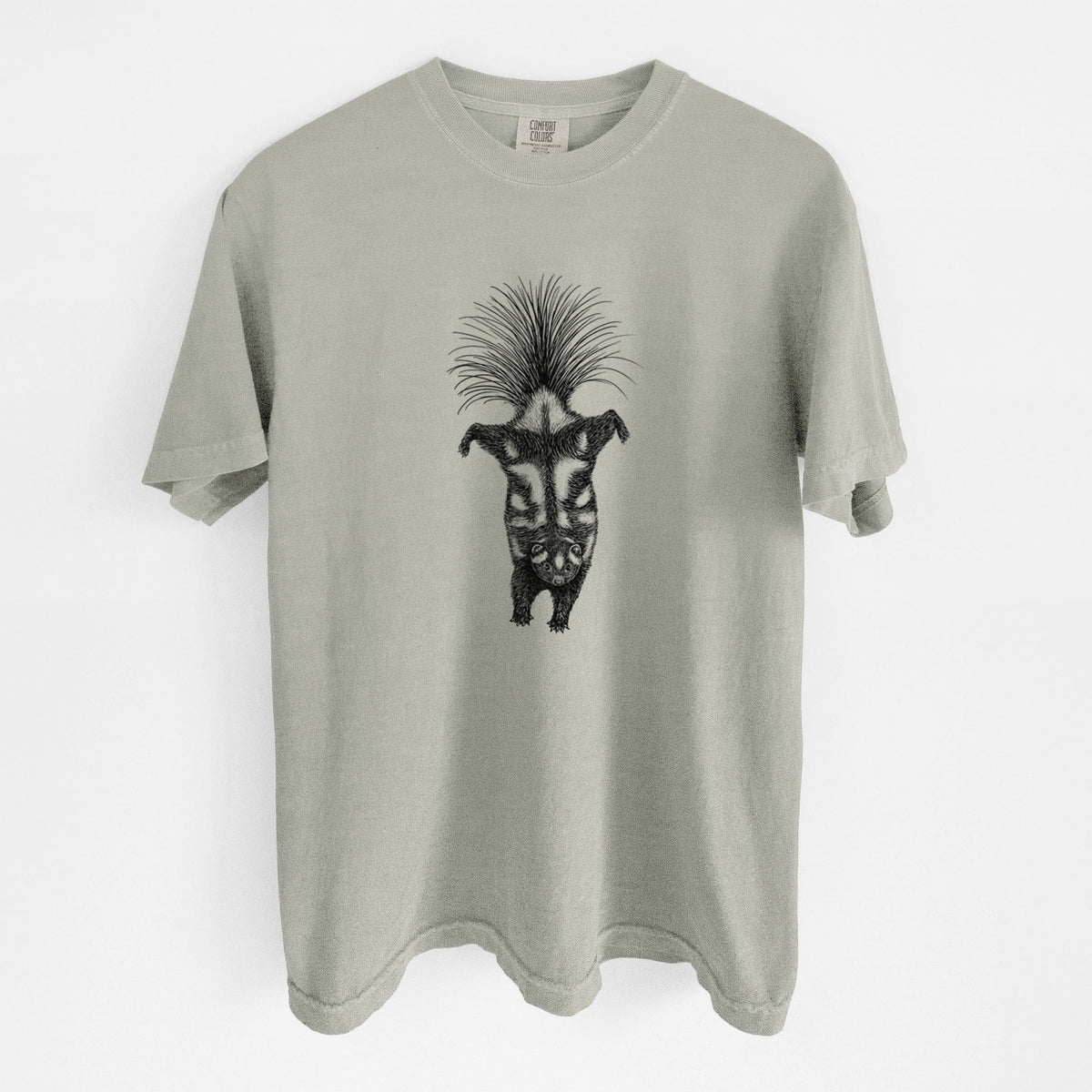 Sandstone beige Comfort Colors t-shirt laid flat, printed with a black ink illustration of a spotted skunk doing a handstand with its tail fanned.