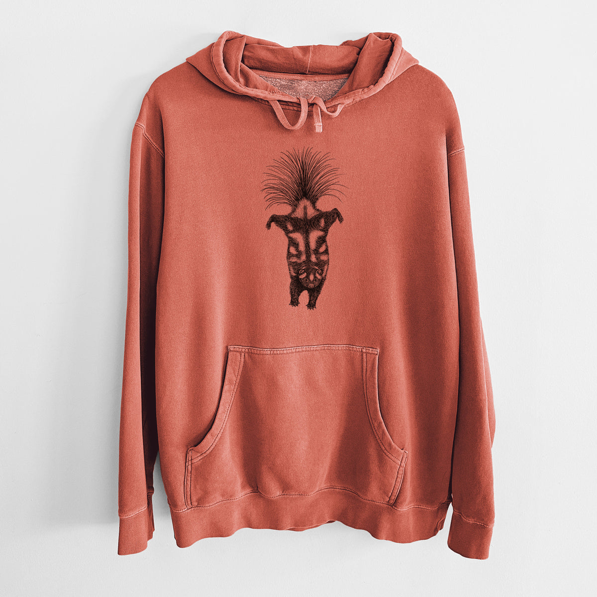 Amber orange pigment dyed hoodie laid flat, printed with a black ink illustration of a spotted skunk doing a handstand with its tail fanned.