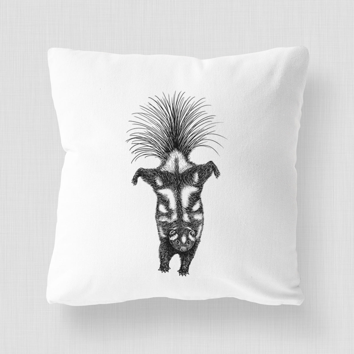 White pillow cover printed with a black ink illustration of a spotted skunk doing a handstand with its tail fanned.