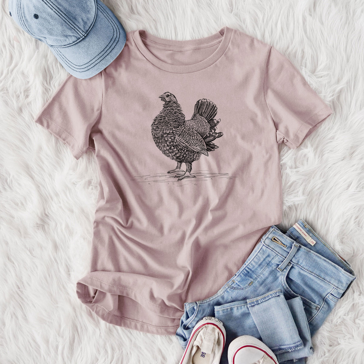 Women's relaxed fit cotton t-shirt printed with a detailed black ink illustration of a spruce grouse standing with its tail fanned, styled flat on a white faux fur rug with jeans.
