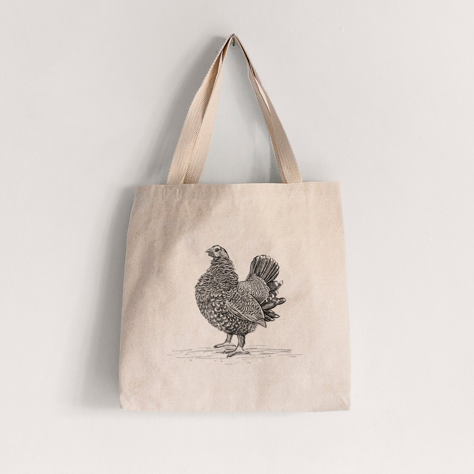 Natural canvas tote bag printed with a detailed black ink illustration of a spruce grouse standing with its tail fanned.