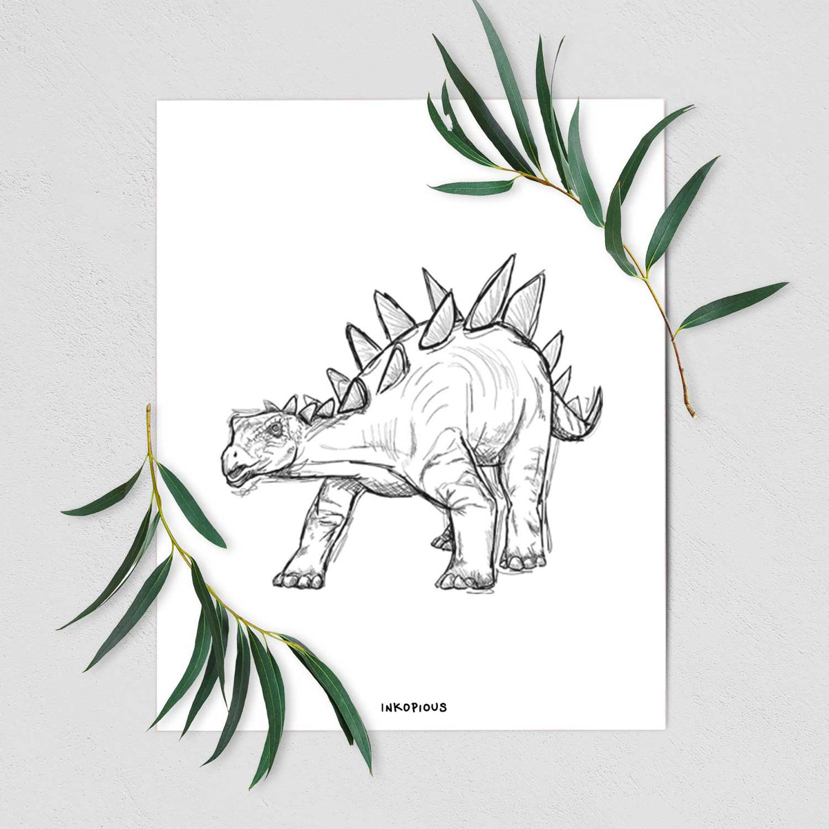Art print of a black ink illustration of a Stegosaurus with plates along its back, shown with eucalyptus leaves.