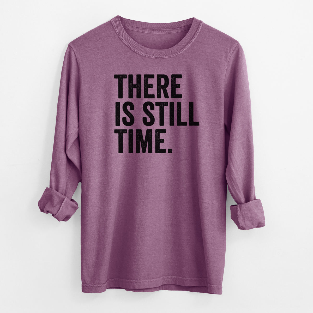 Berry pink Comfort Colors long sleeve shirt laid flat with the cuffs rolled, printed with bold black words reading There Is Still Time.