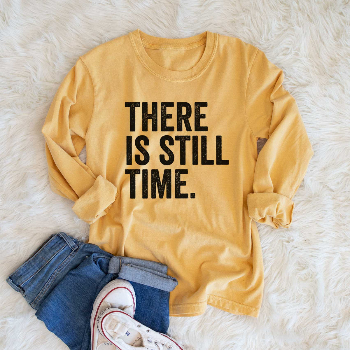 Golden wheat yellow Comfort Colors long sleeve shirt printed with bold black words reading There Is Still Time, shown in a lifestyle photo.