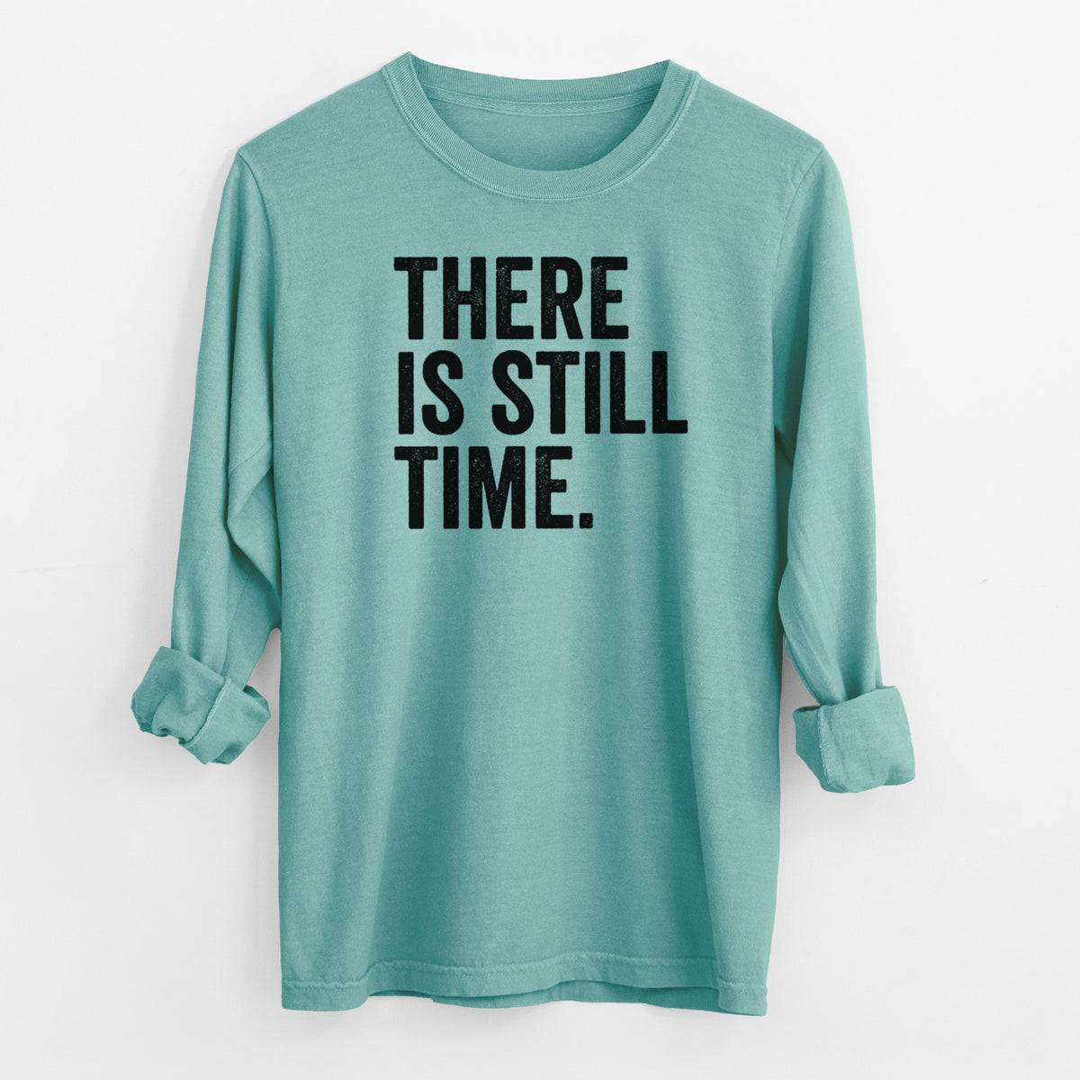 Reef green Comfort Colors long sleeve shirt laid flat with the cuffs rolled, printed with bold black words reading There Is Still Time.