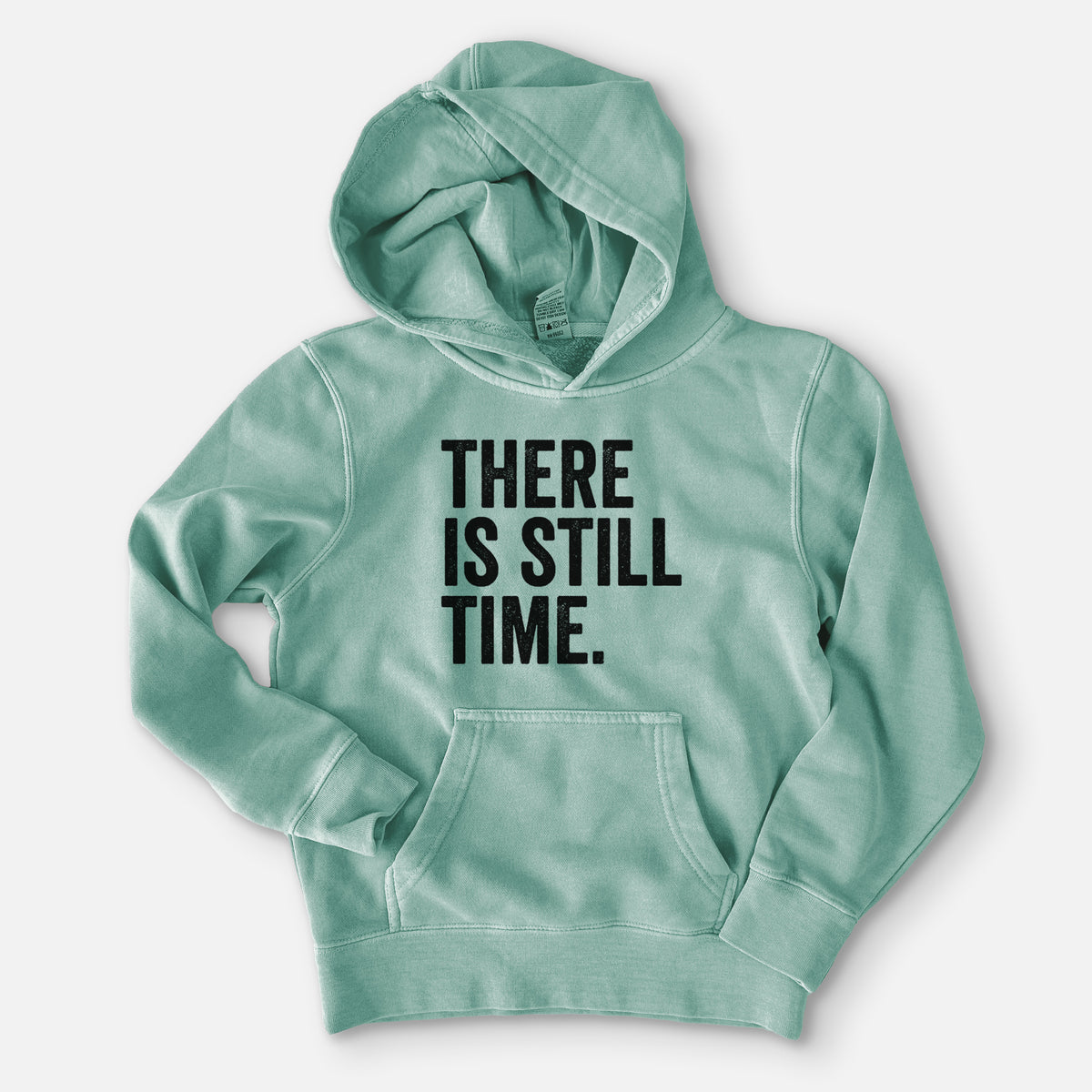 Sea green youth pigment dyed hoodie laid flat, printed with bold black words reading There Is Still Time.