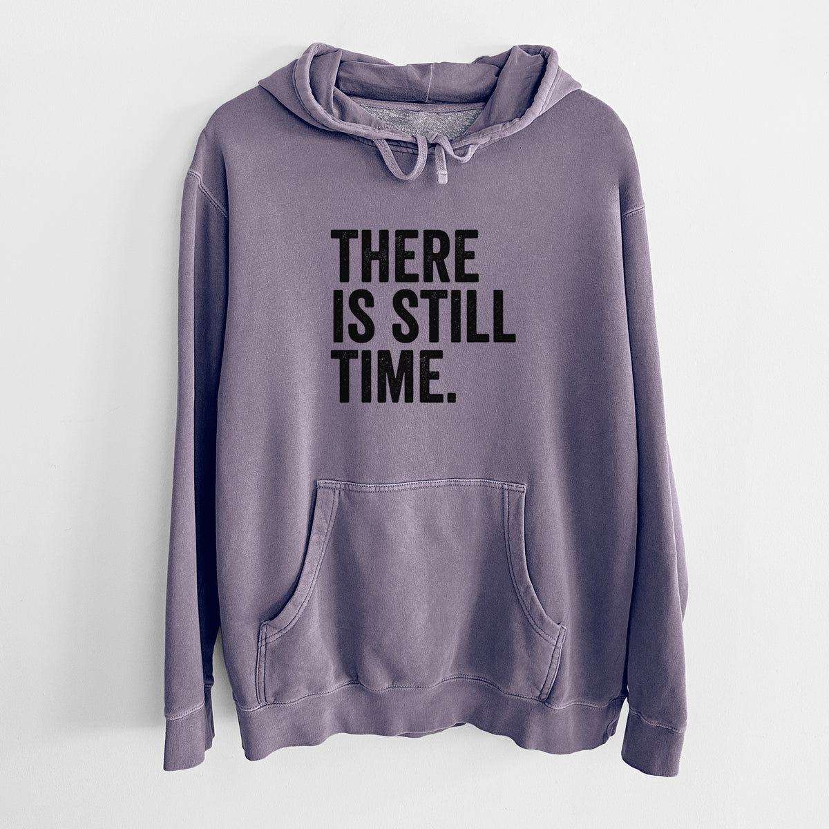 Plum purple pigment dyed hoodie laid flat, printed with bold black words reading There Is Still Time.