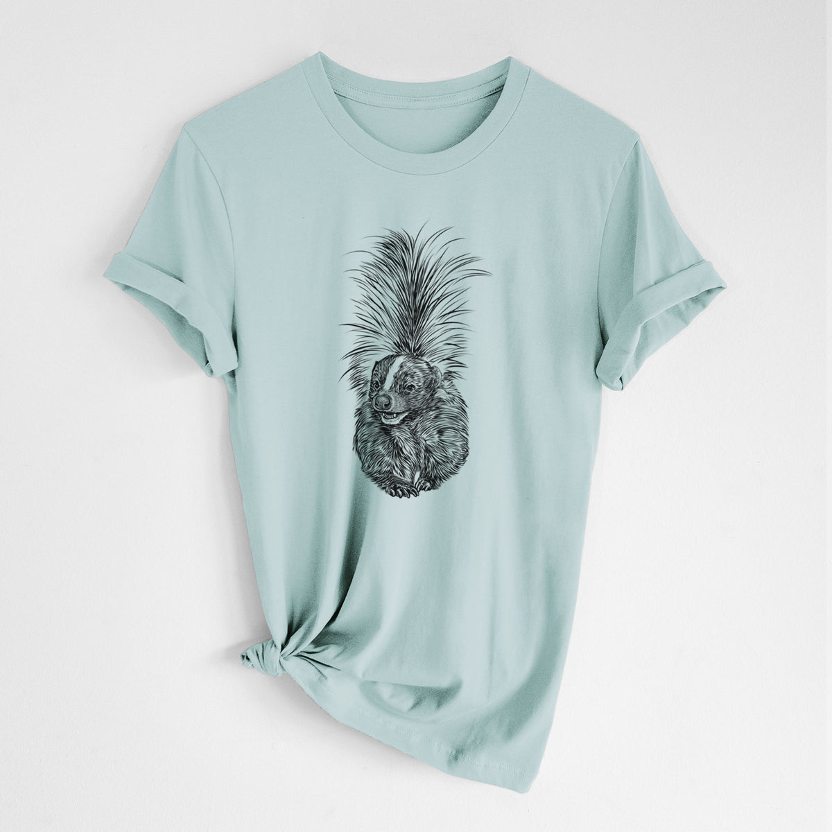 Dusty blue lightweight cotton t-shirt laid flat with the sleeves rolled, printed with a detailed black ink illustration of a striped skunk with its tail raised.