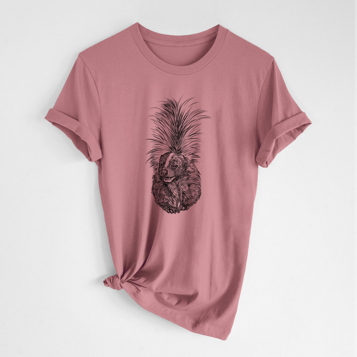 Mauve pink lightweight cotton t-shirt laid flat with the sleeves rolled, printed with a detailed black ink illustration of a striped skunk with its tail raised.