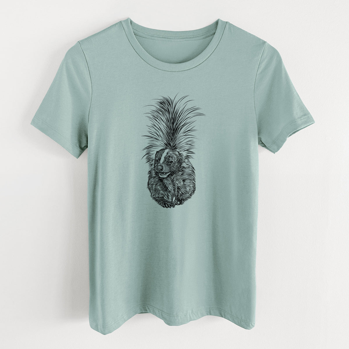 Dusty blue women's relaxed fit cotton t-shirt laid flat, printed with a detailed black ink illustration of a striped skunk with its tail raised.