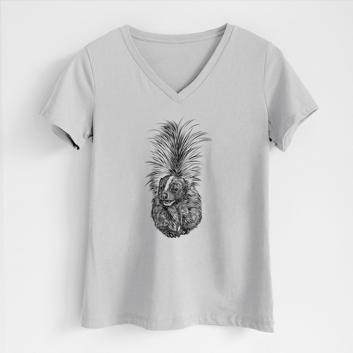 Lunar grey women's relaxed fit cotton V-neck t-shirt laid flat, printed with a detailed black ink illustration of a striped skunk with its tail raised.