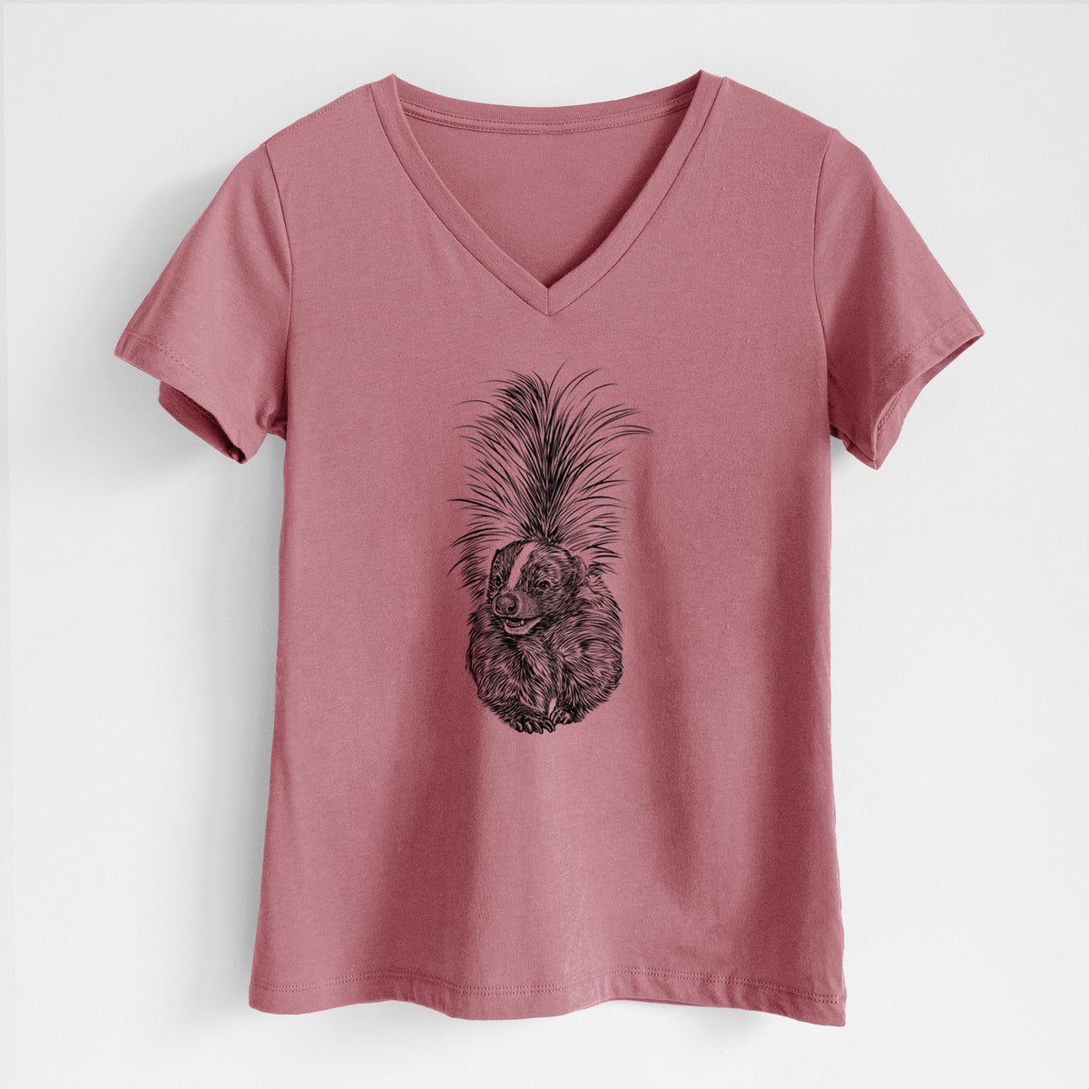 Mauve pink women's relaxed fit cotton V-neck t-shirt laid flat, printed with a detailed black ink illustration of a striped skunk with its tail raised.