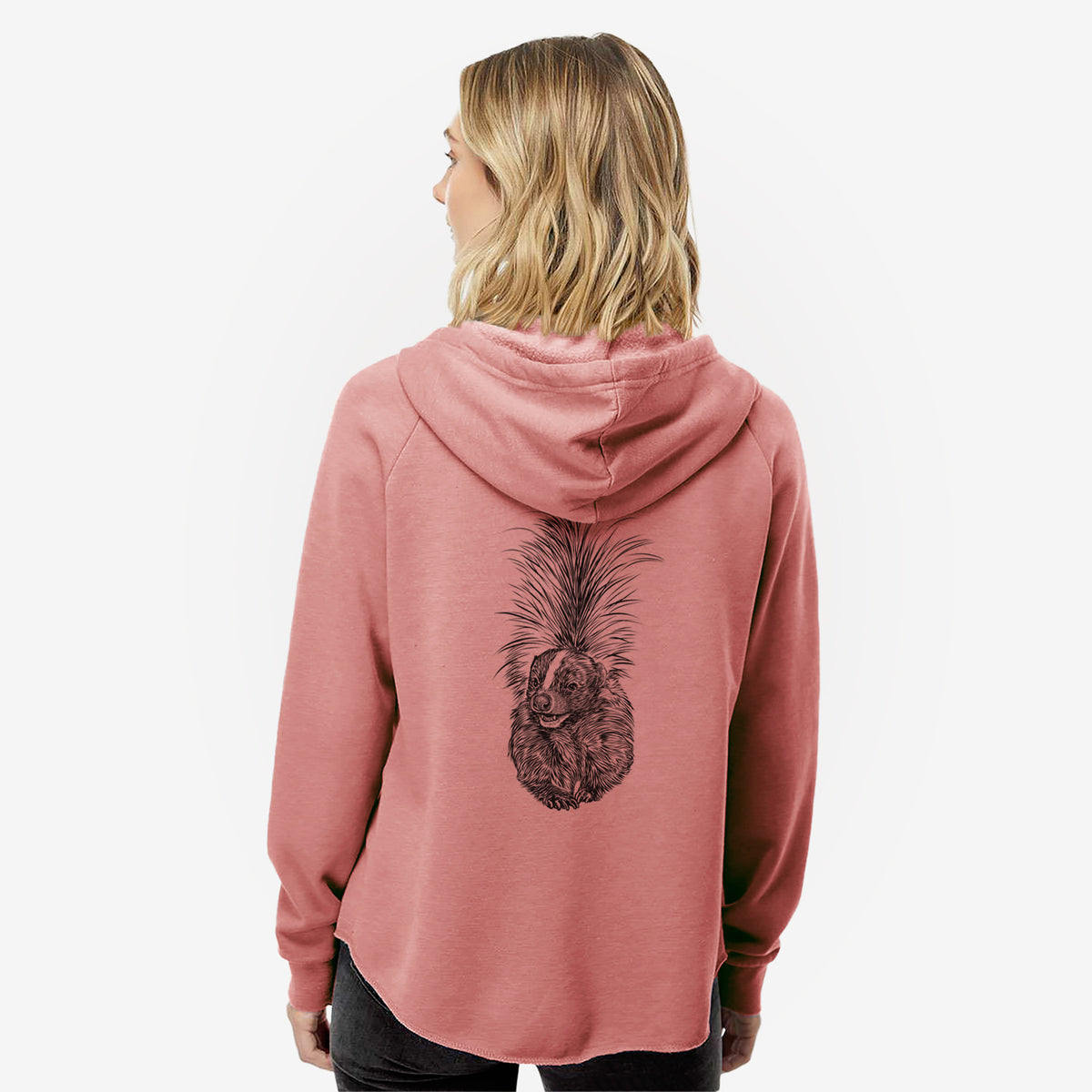 Woman wearing a dusty rose women's Cali Wave zip-up sweatshirt printed with a detailed black ink illustration of a striped skunk with its tail raised, seen from behind.