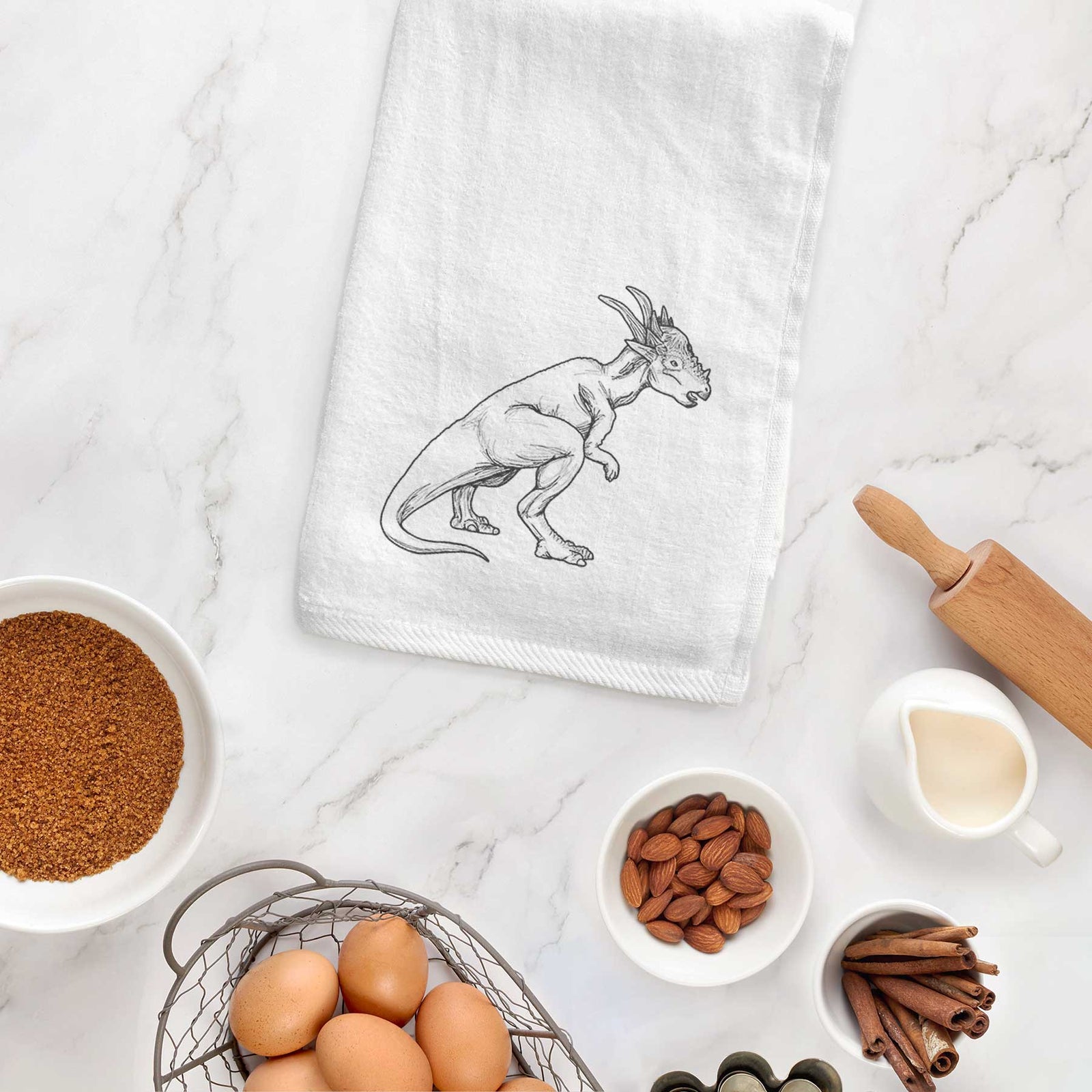White hand towel printed with a black ink illustration of a Stygimoloch dinosaur with a spiky domed head.