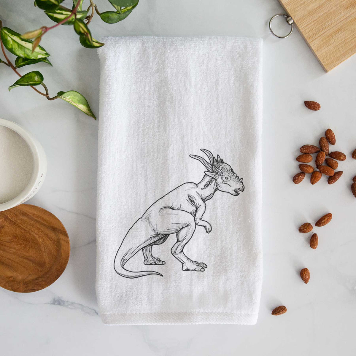White hand towel printed with a black ink illustration of a Stygimoloch dinosaur with a spiky domed head.