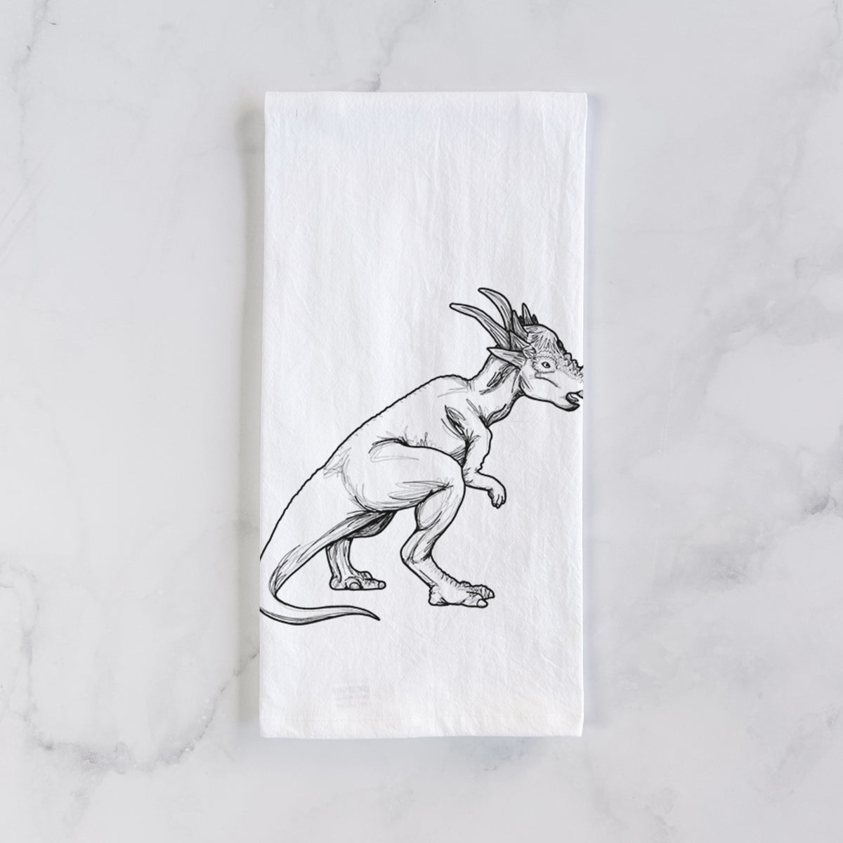 White cotton tea towel laid flat on marble, printed with a black ink illustration of a Stygimoloch dinosaur with a spiky domed head.