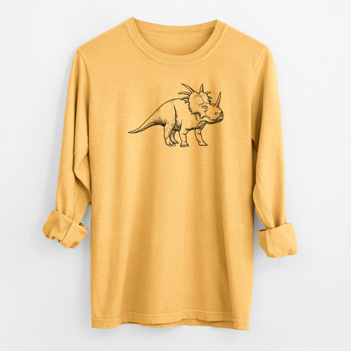 Golden wheat yellow Comfort Colors long sleeve shirt laid flat with the cuffs rolled, printed with a black ink illustration of a Styracosaurus with its spiked frill.