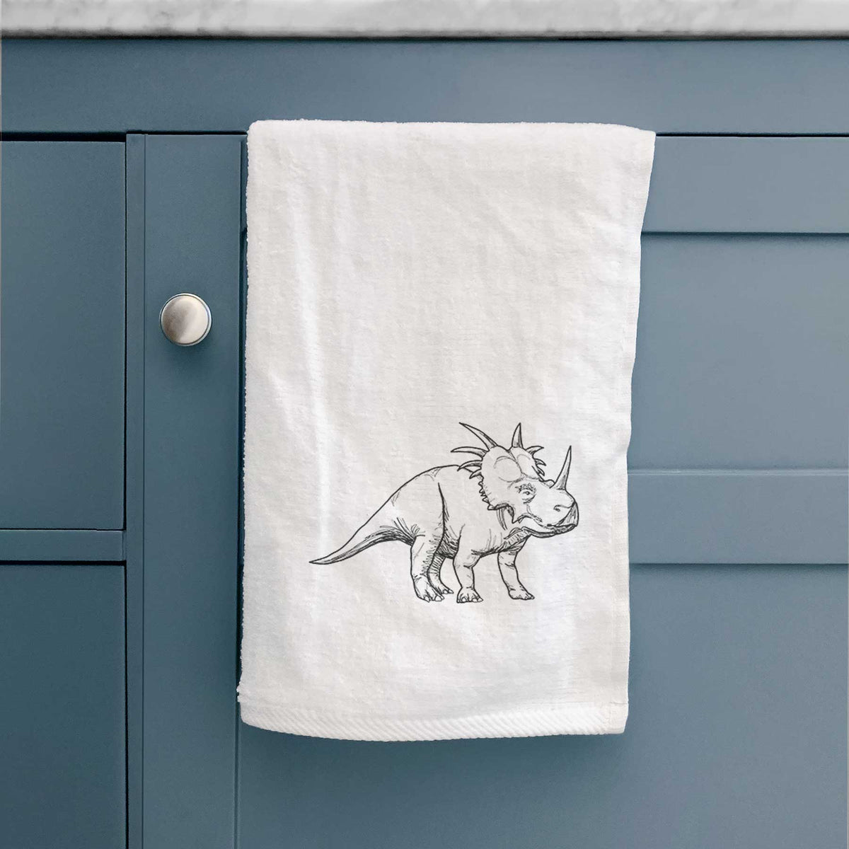 White hand towel printed with a black ink illustration of a Styracosaurus with its spiked frill.