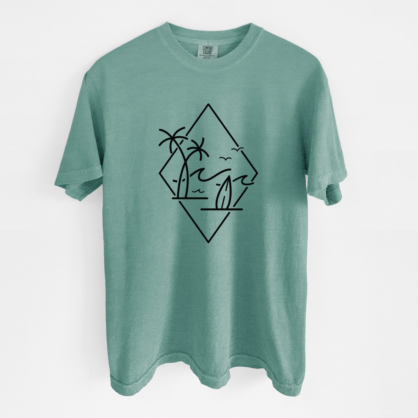 Blue jean Comfort Colors t-shirt laid flat, printed with black line art of palm trees, ocean waves, birds and a surfboard inside a diamond outline.