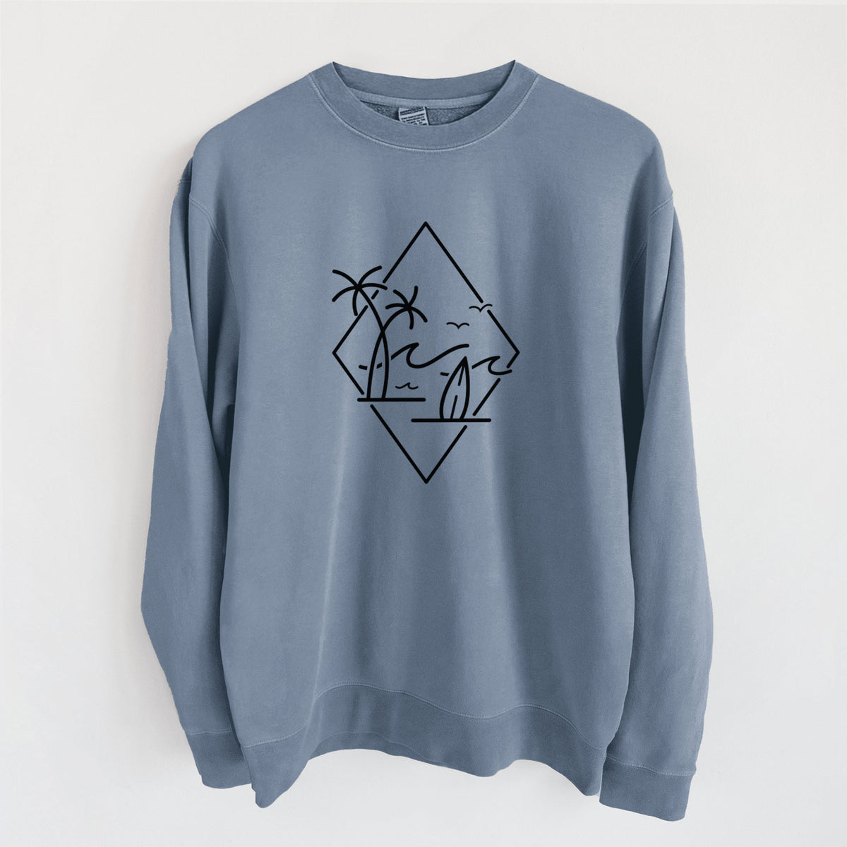 Slate blue pigment dyed crewneck sweatshirt laid flat, printed with black line art of palm trees, ocean waves, birds and a surfboard inside a diamond outline.