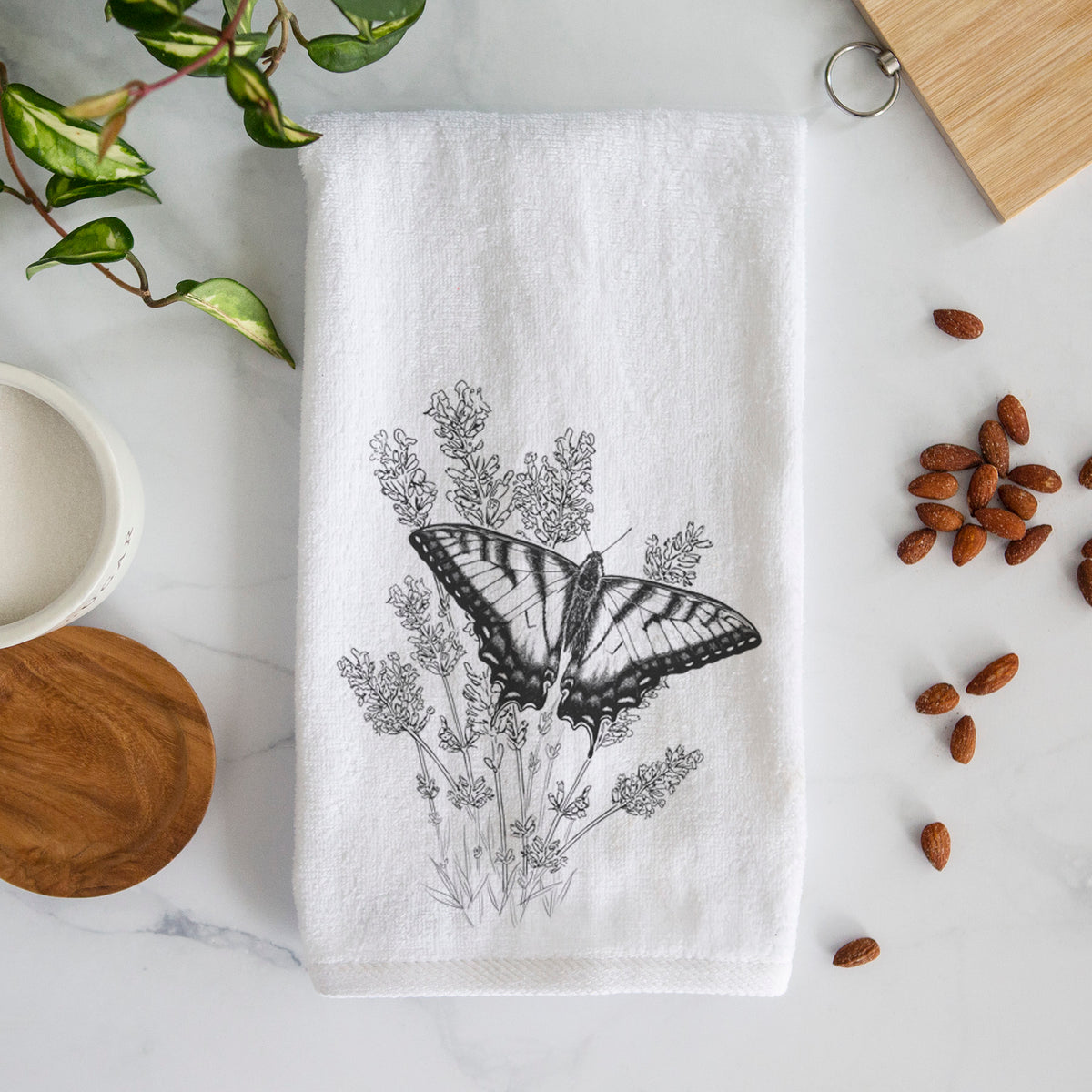 White hand towel printed with a black ink illustration of a swallowtail butterfly resting on lavender.