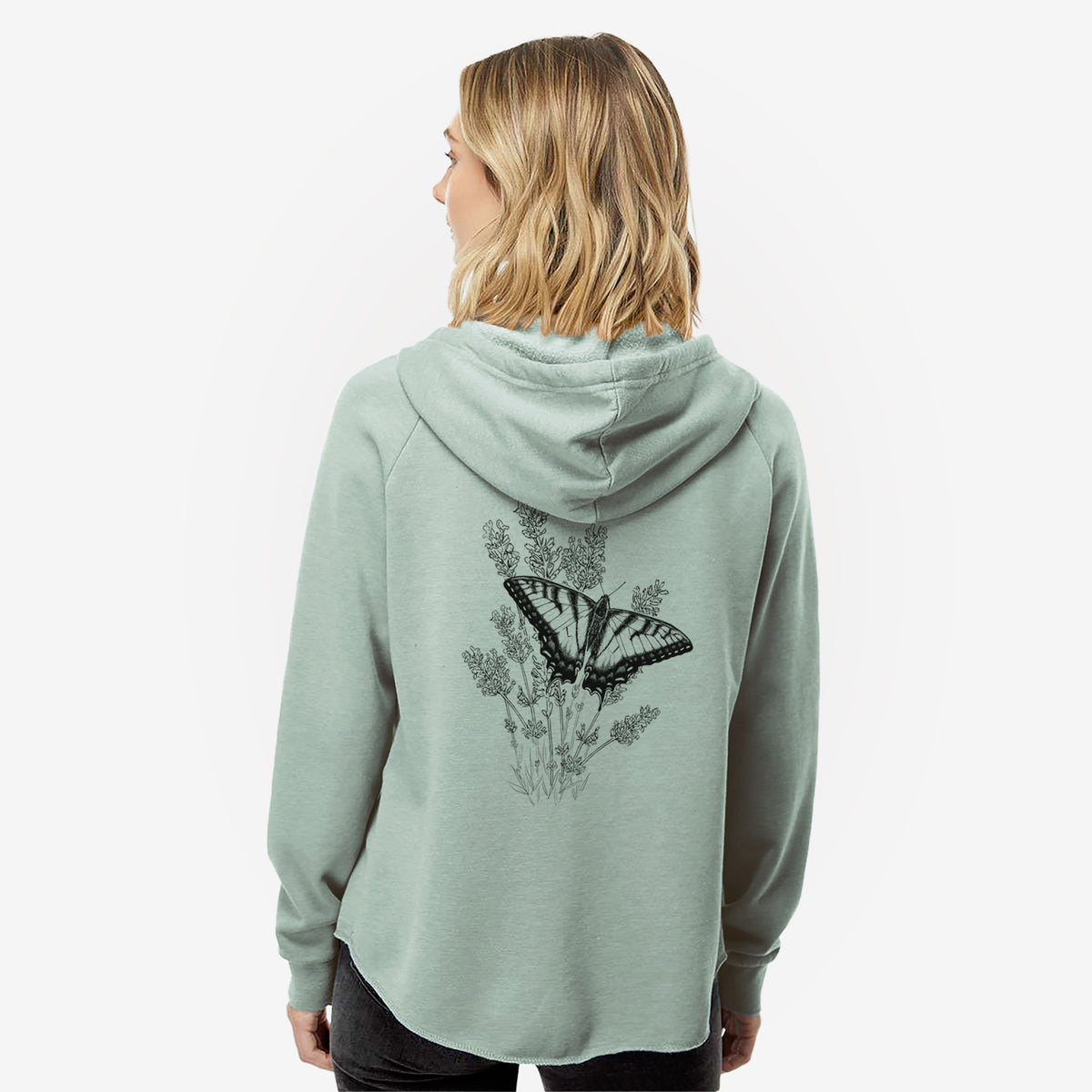 Woman wearing a sage green women's Cali Wave zip-up sweatshirt printed with a black ink illustration of a swallowtail butterfly resting on lavender, seen from behind.