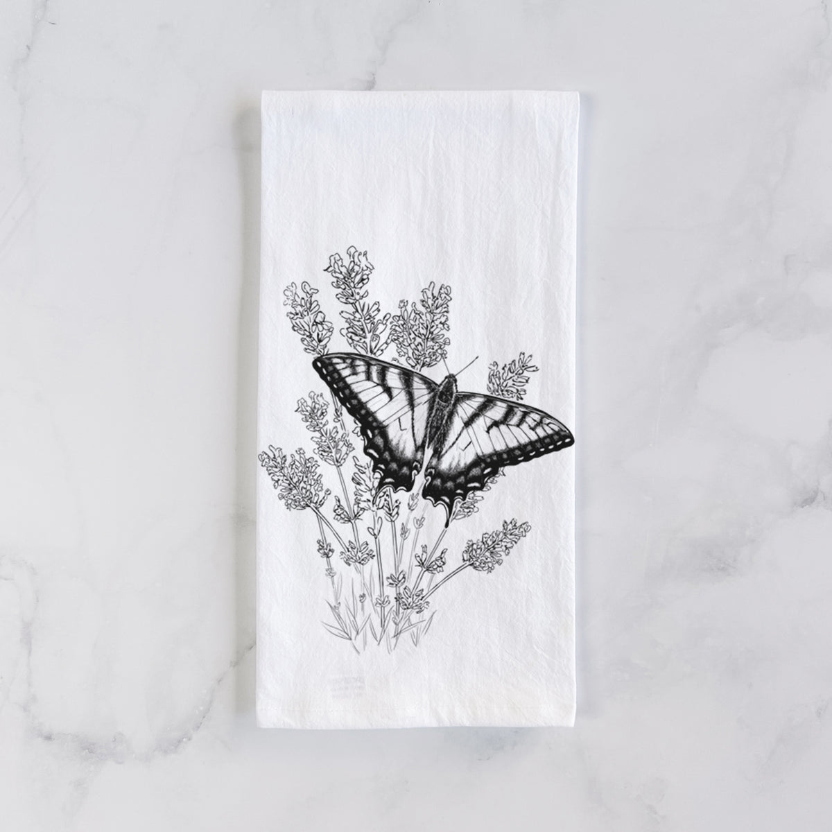White cotton tea towel laid flat on marble, printed with a black ink illustration of a swallowtail butterfly resting on lavender.