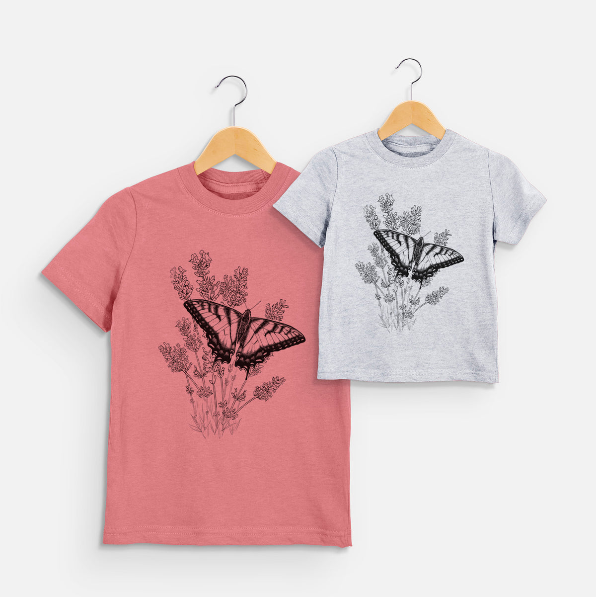 Two youth t-shirts in different colors on hangers, printed with a black ink illustration of a swallowtail butterfly resting on lavender.