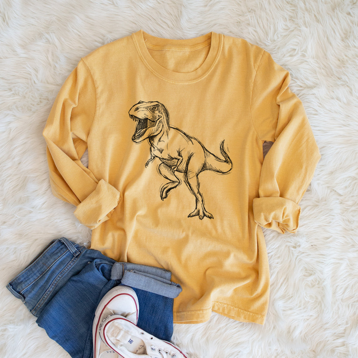 Golden wheat yellow Comfort Colors long sleeve shirt printed with a black ink illustration of a Tyrannosaurus rex roaring, shown in a lifestyle photo.