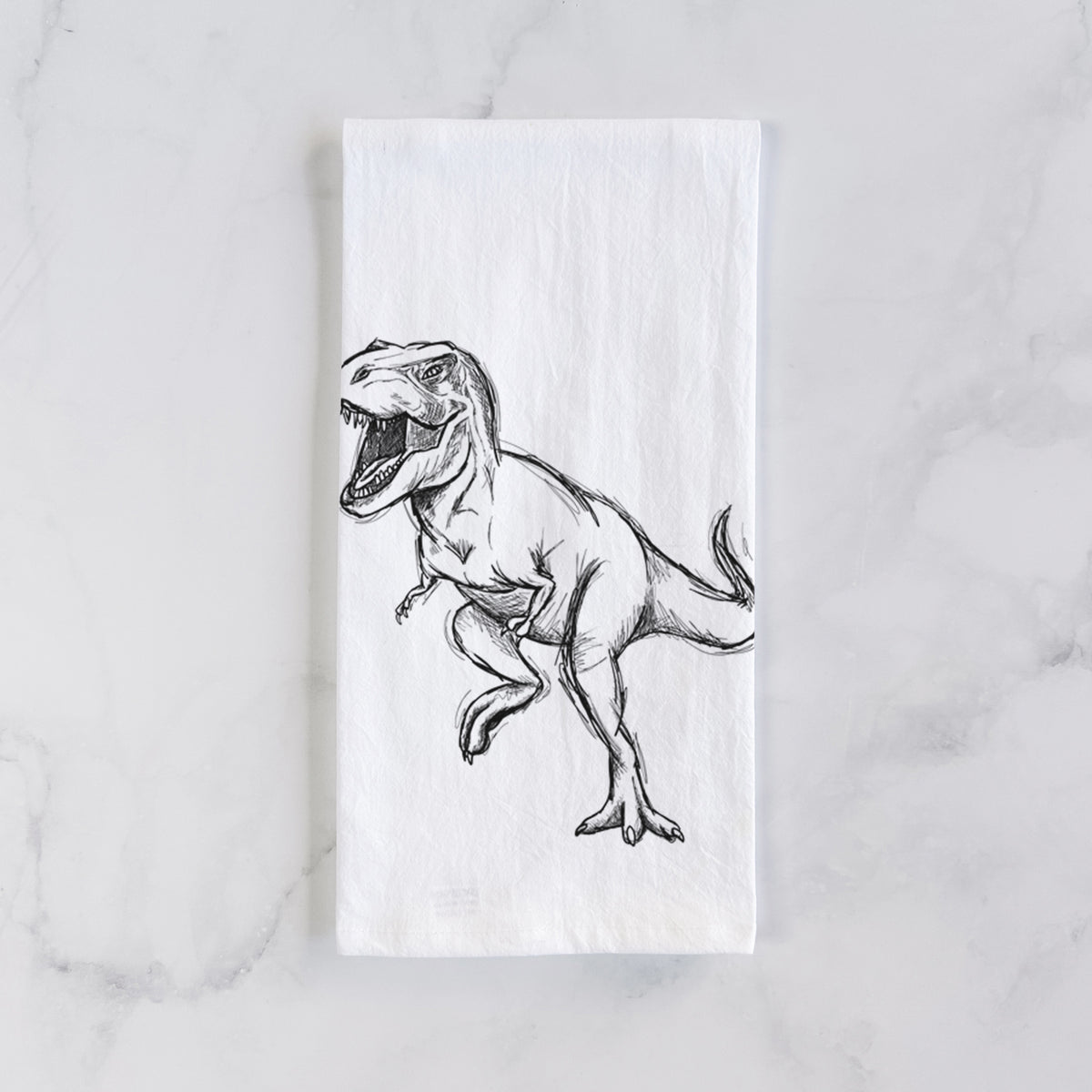 White cotton tea towel laid flat on marble, printed with a black ink illustration of a Tyrannosaurus rex roaring.