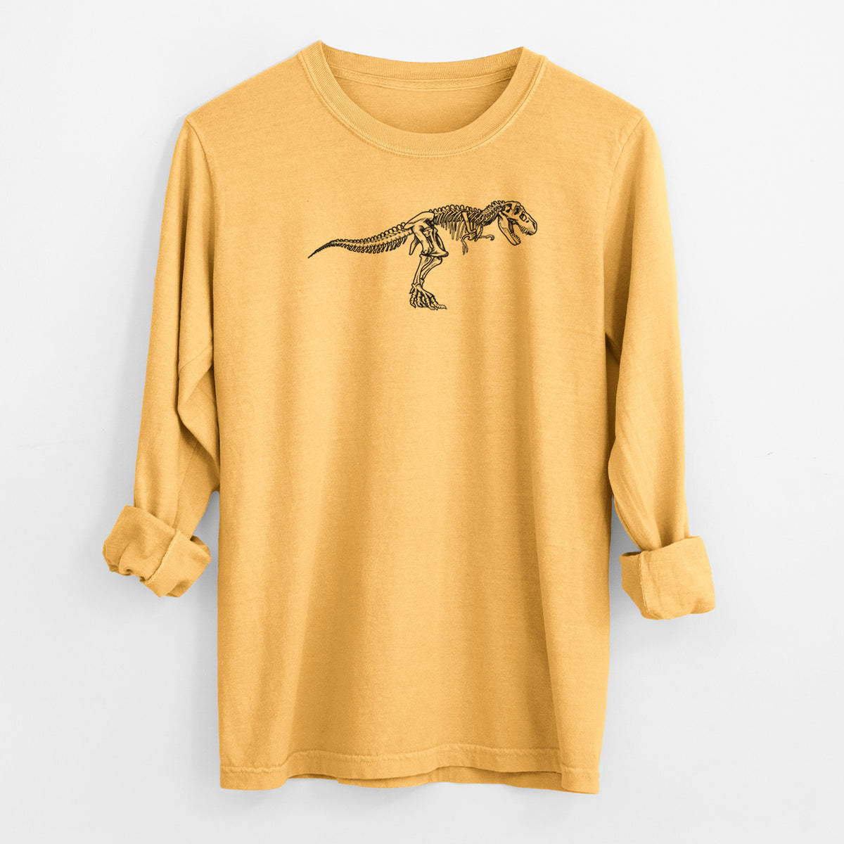 Golden wheat yellow Comfort Colors long sleeve shirt laid flat with the cuffs rolled, printed with a black ink illustration of a Tyrannosaurus rex skeleton.