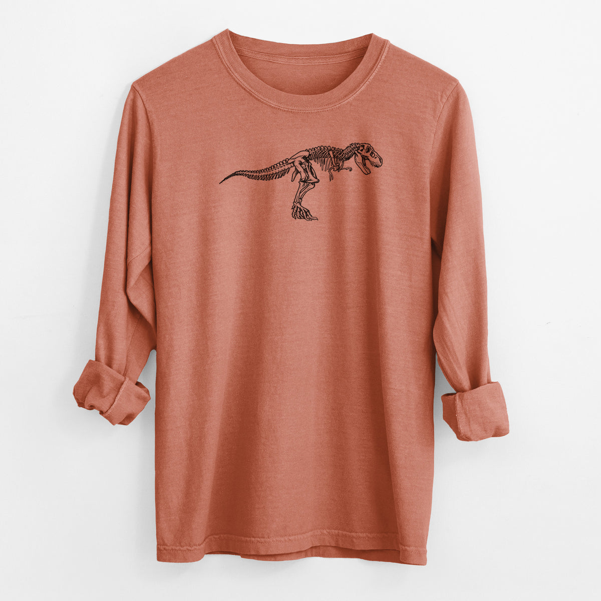 Yam burnt orange Comfort Colors long sleeve shirt laid flat with the cuffs rolled, printed with a black ink illustration of a Tyrannosaurus rex skeleton.