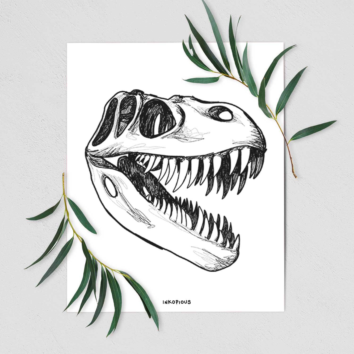 Art print of a black ink illustration of a Tyrannosaurus rex skull with sharp teeth, shown with eucalyptus leaves.