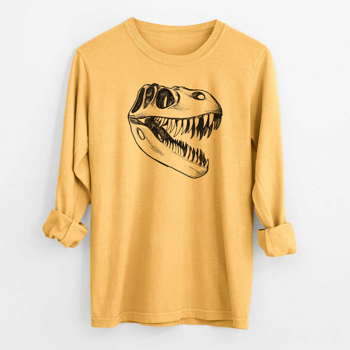 Golden wheat yellow Comfort Colors long sleeve shirt laid flat with the cuffs rolled, printed with a black ink illustration of a Tyrannosaurus rex skull with sharp teeth.