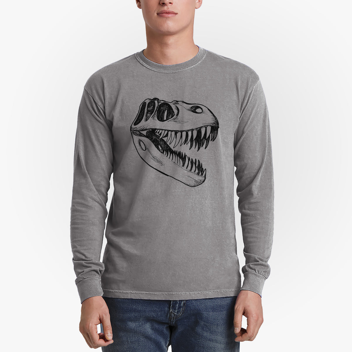 Man wearing a grey Comfort Colors long sleeve shirt printed with a black ink illustration of a Tyrannosaurus rex skull with sharp teeth.
