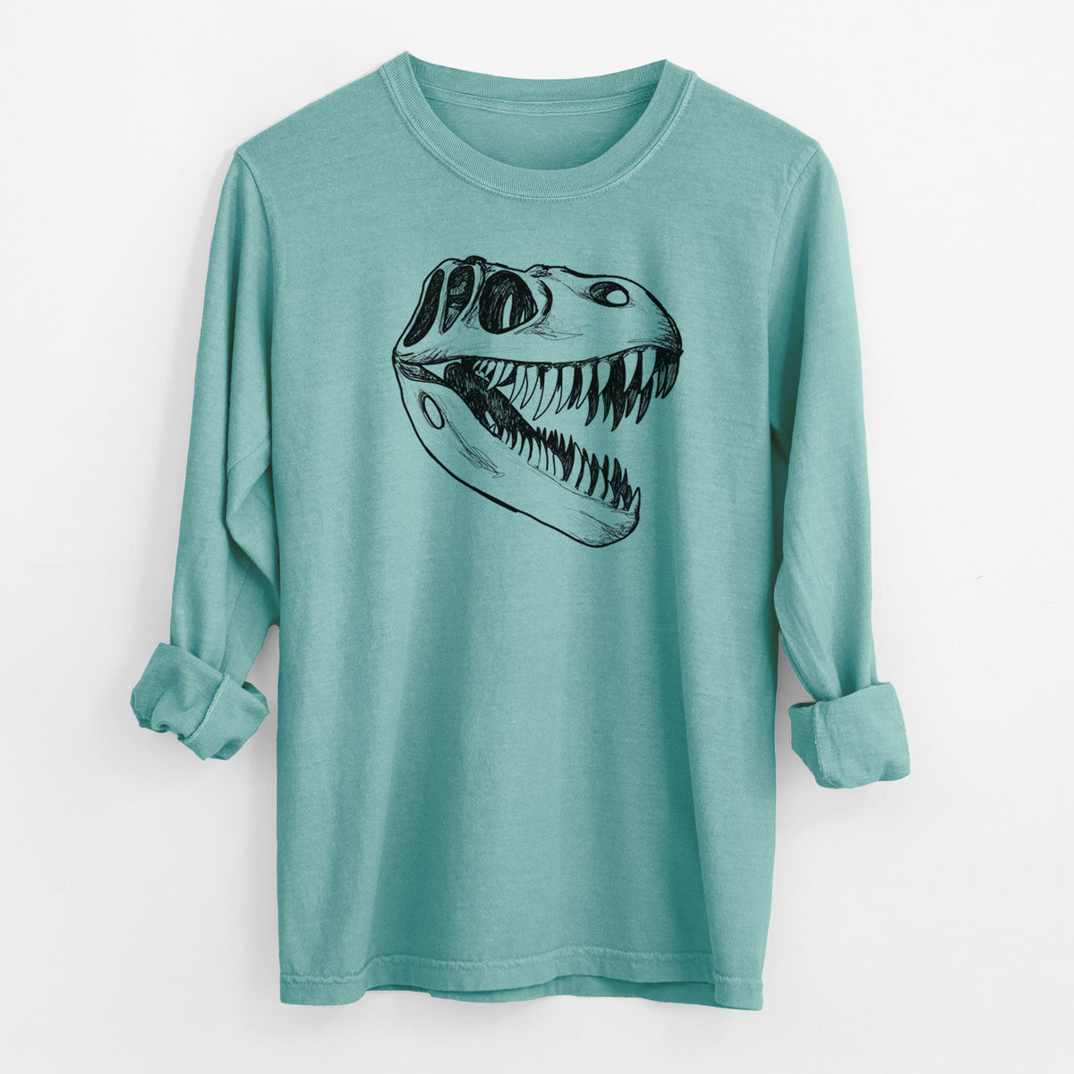 Reef green Comfort Colors long sleeve shirt laid flat with the cuffs rolled, printed with a black ink illustration of a Tyrannosaurus rex skull with sharp teeth.