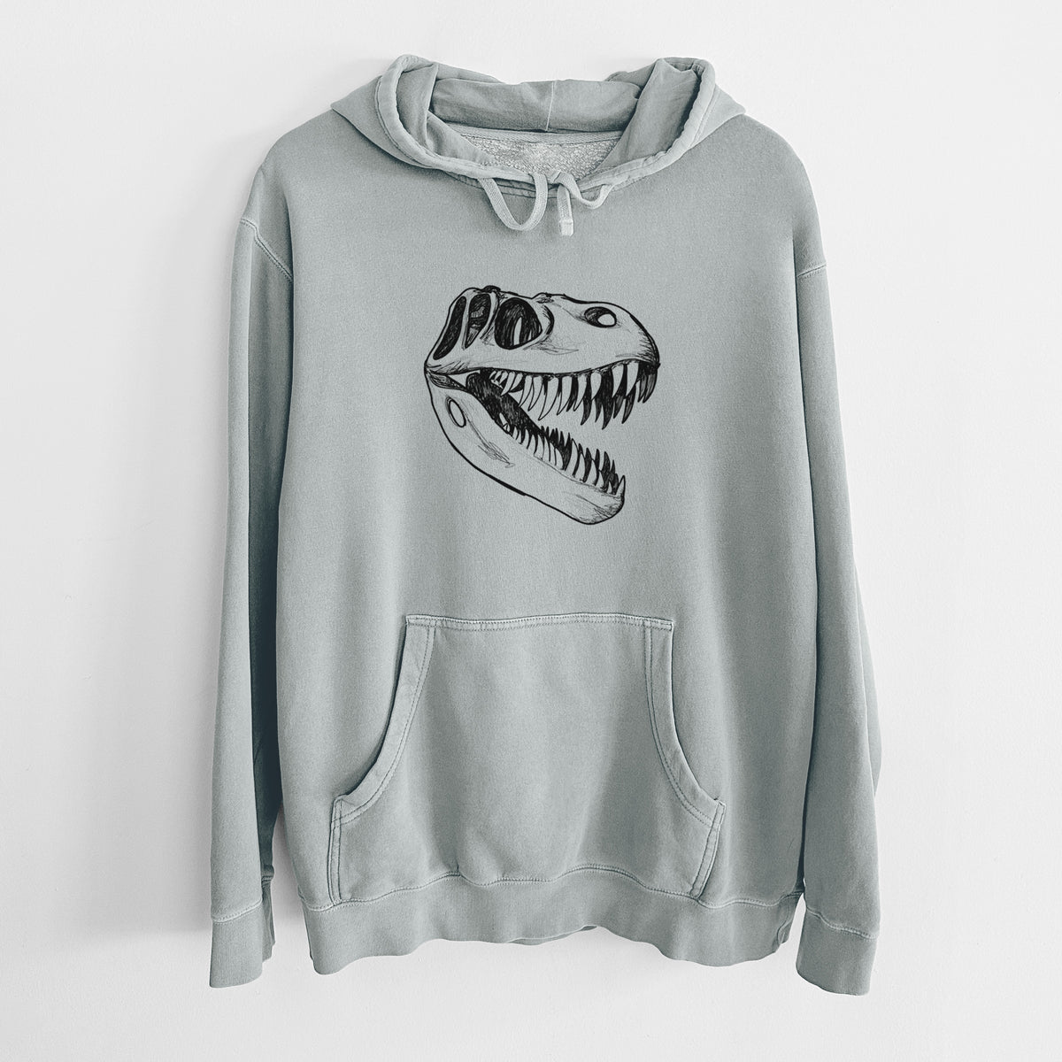 Sage green pigment dyed hoodie laid flat, printed with a black ink illustration of a Tyrannosaurus rex skull with sharp teeth.