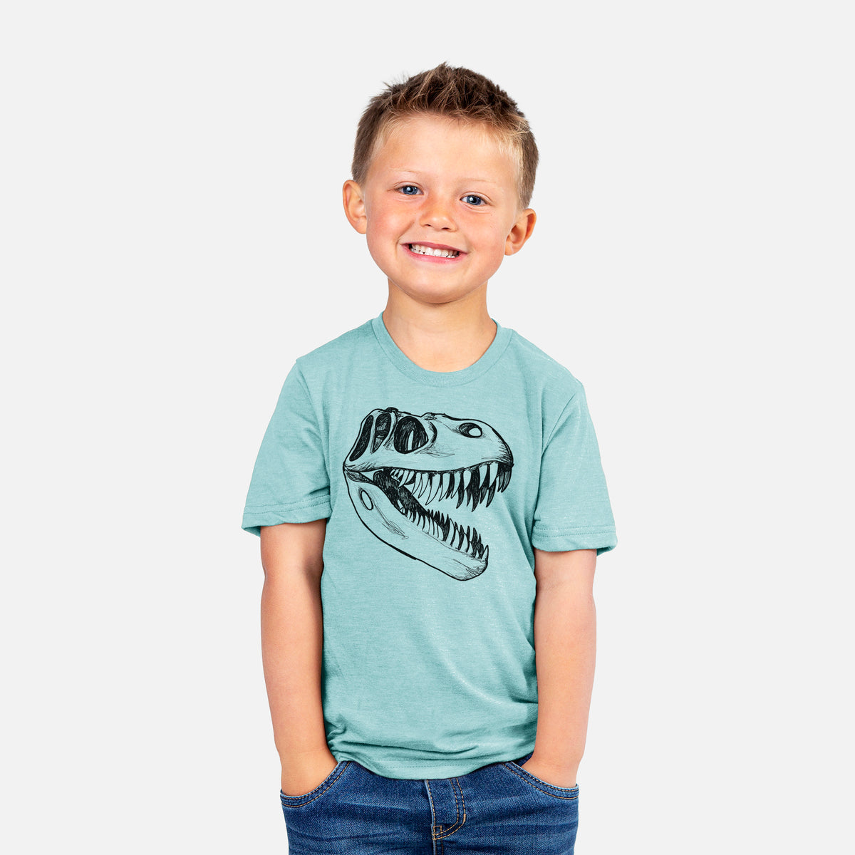 Smiling boy wearing a youth t-shirt printed with a black ink illustration of a Tyrannosaurus rex skull with sharp teeth.