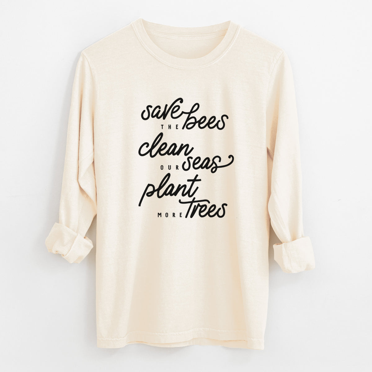 Ivory Comfort Colors long sleeve shirt laid flat with the cuffs rolled, printed with black hand-lettered words reading Save the Bees, Clean Our Seas, Plant More Trees.