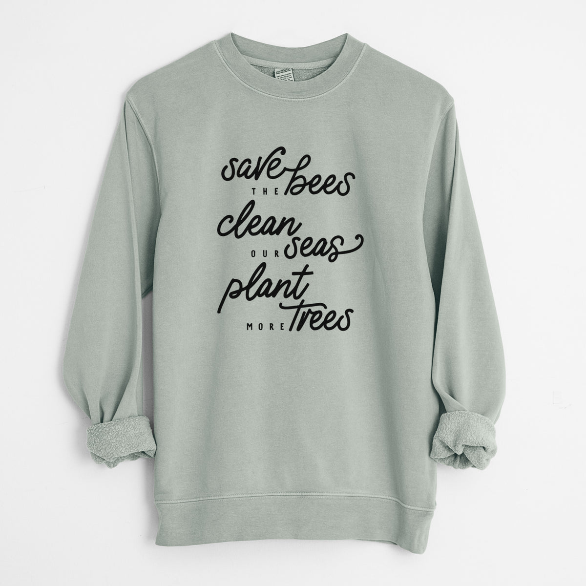 Sage green pigment dyed crewneck sweatshirt laid flat with the sleeves rolled, printed with black hand-lettered words reading Save the Bees, Clean Our Seas, Plant More Trees.