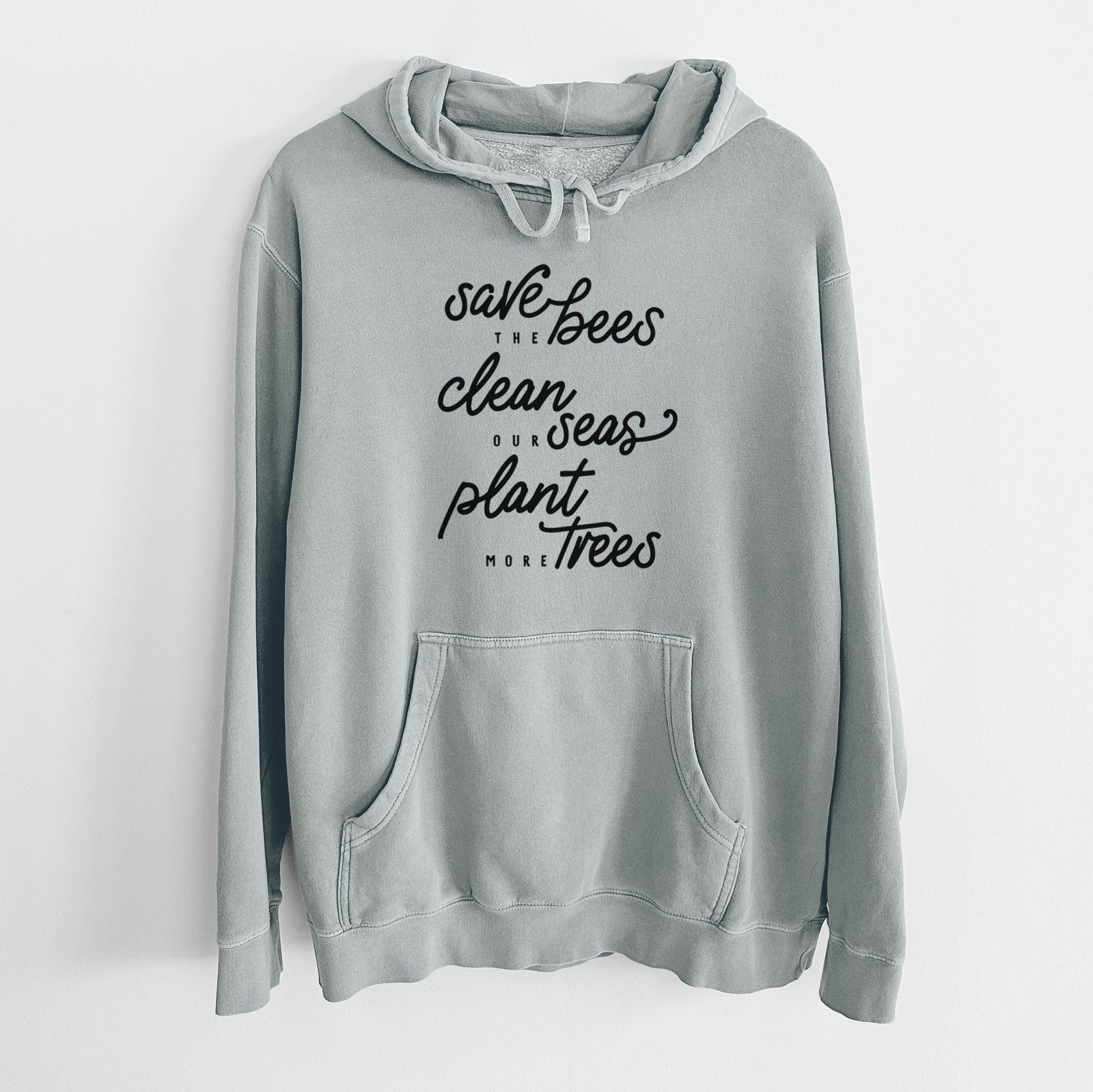 Sage green pigment dyed hoodie laid flat, printed with black hand-lettered words reading Save the Bees, Clean Our Seas, Plant More Trees.