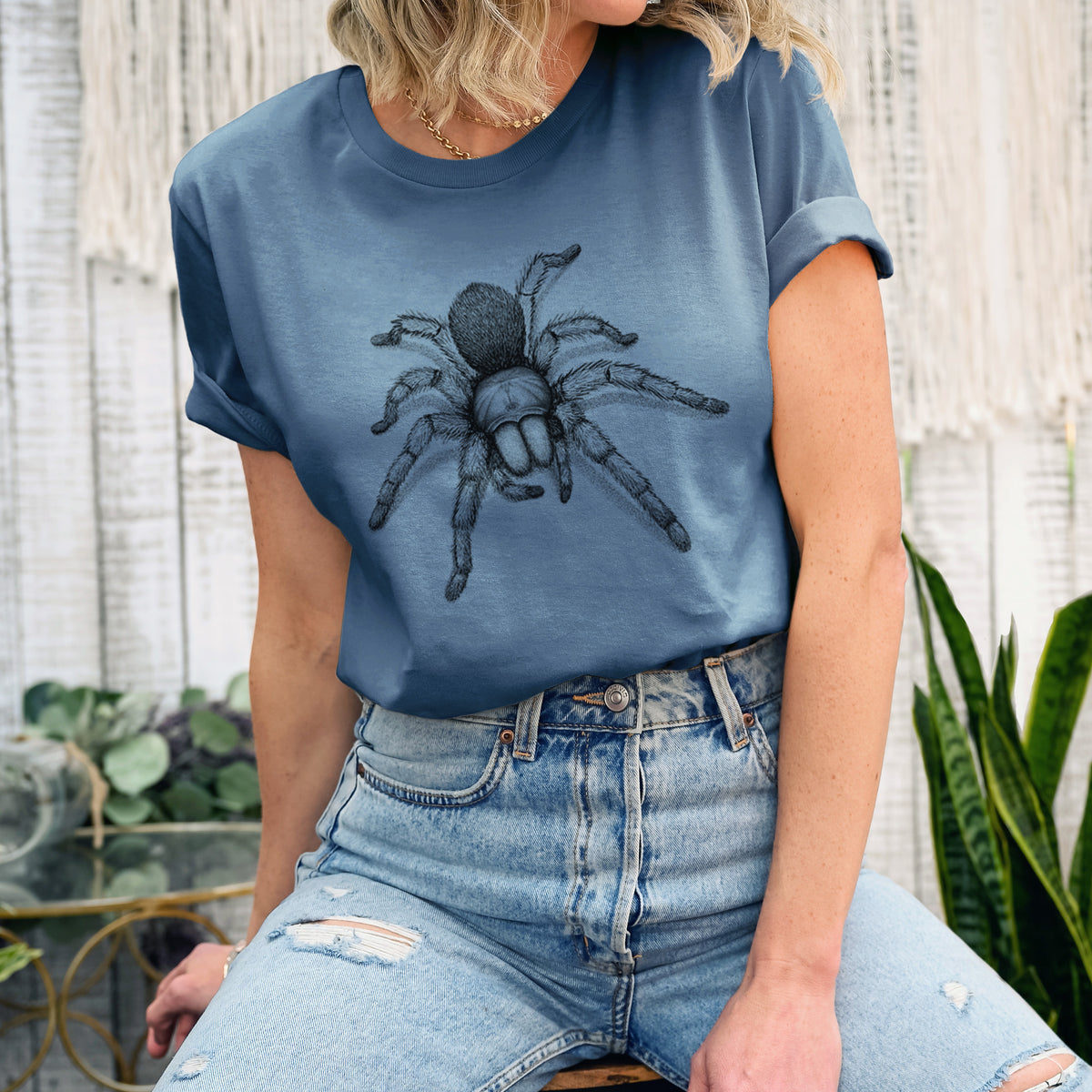 Woman wearing a steel blue lightweight cotton t-shirt printed with a detailed black ink illustration of a desert blonde tarantula.