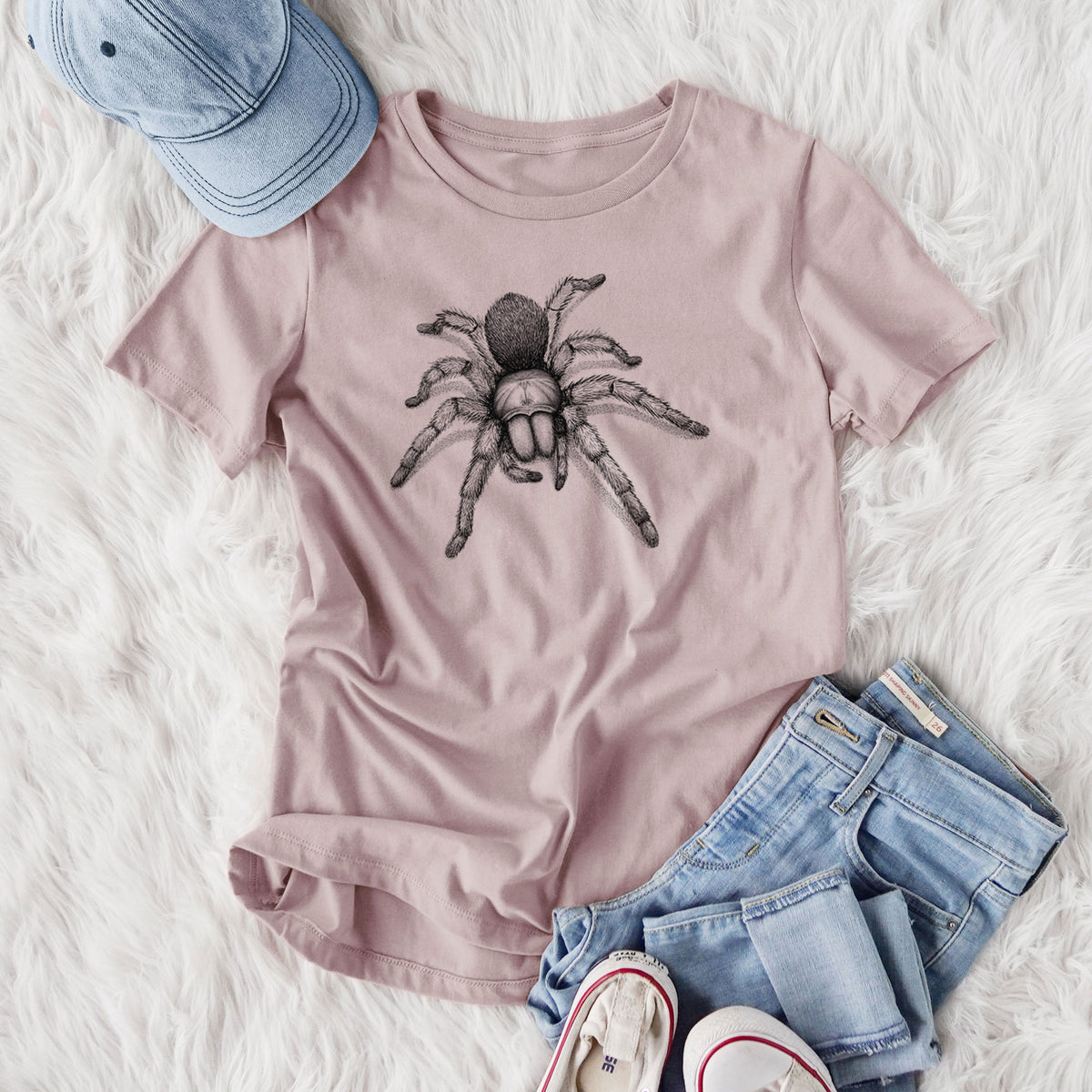 Women's relaxed fit cotton t-shirt printed with a detailed black ink illustration of a desert blonde tarantula, styled flat on a white faux fur rug with jeans.