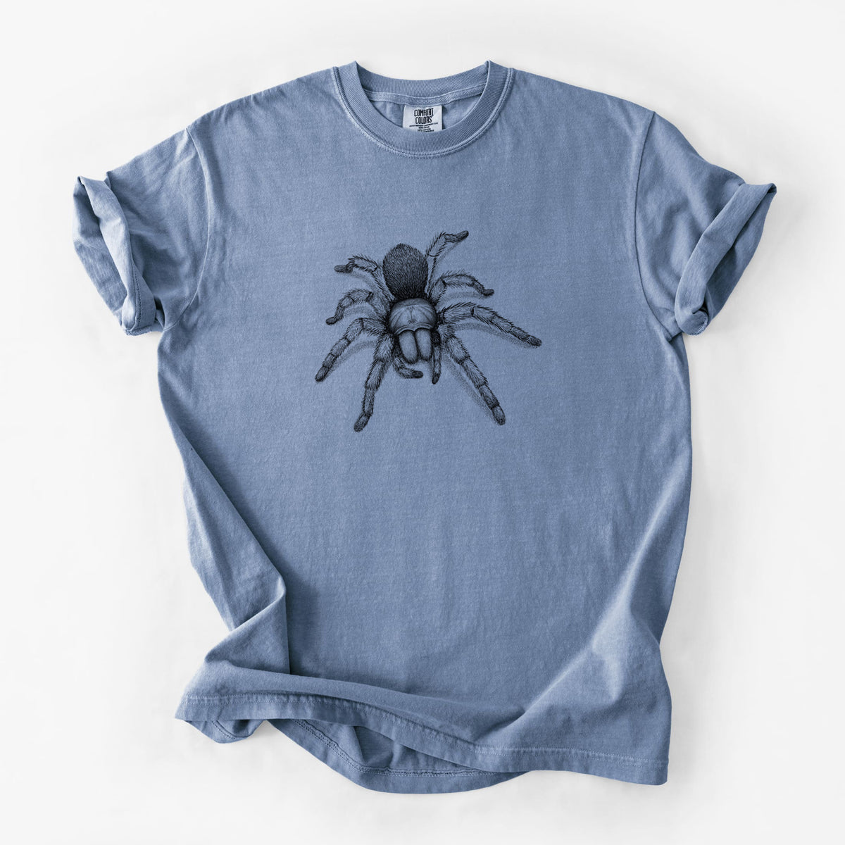 Blue jean Comfort Colors t-shirt laid flat, printed with a detailed black ink illustration of a desert blonde tarantula.