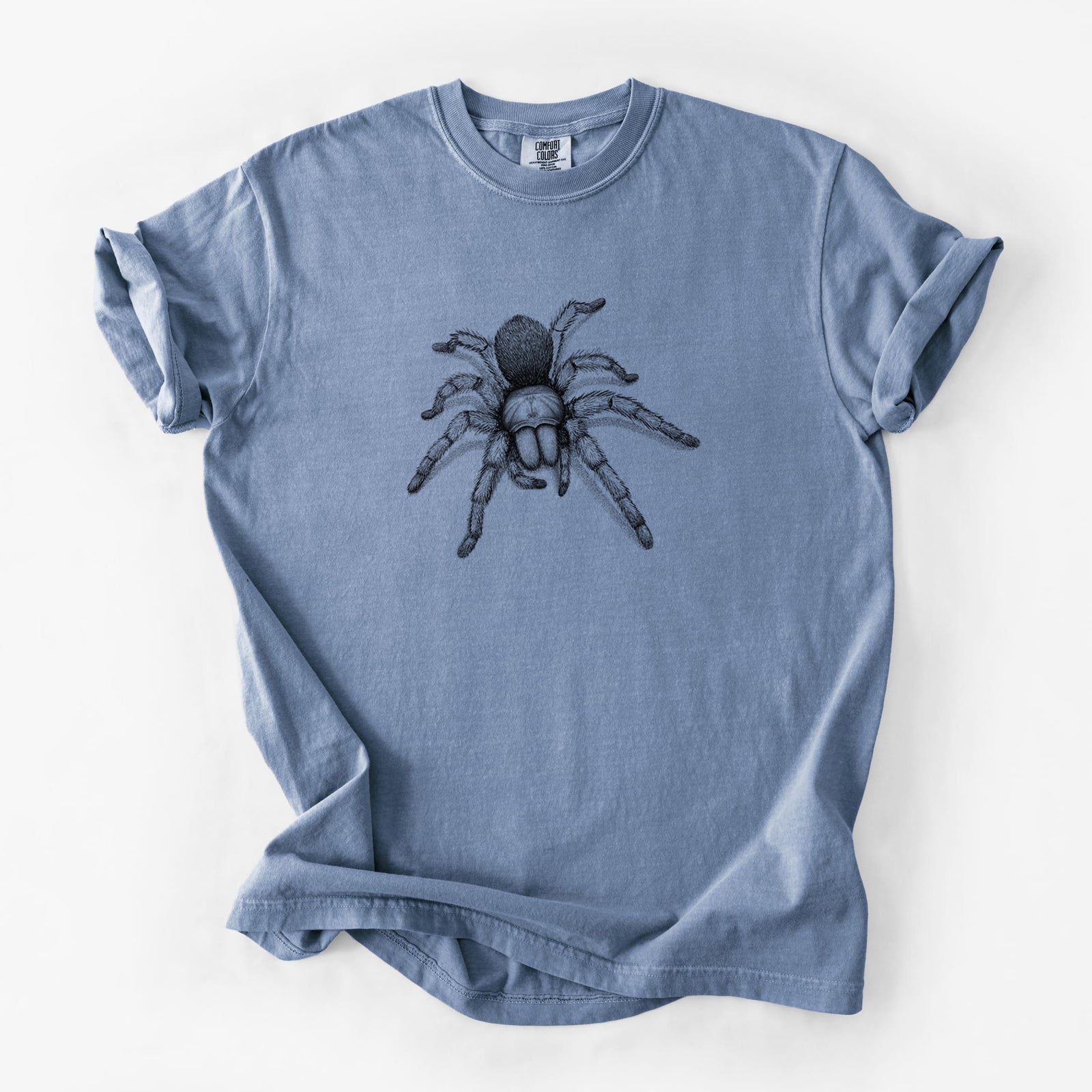 Blue jean Comfort Colors t-shirt laid flat, printed with a detailed black ink illustration of a desert blonde tarantula.