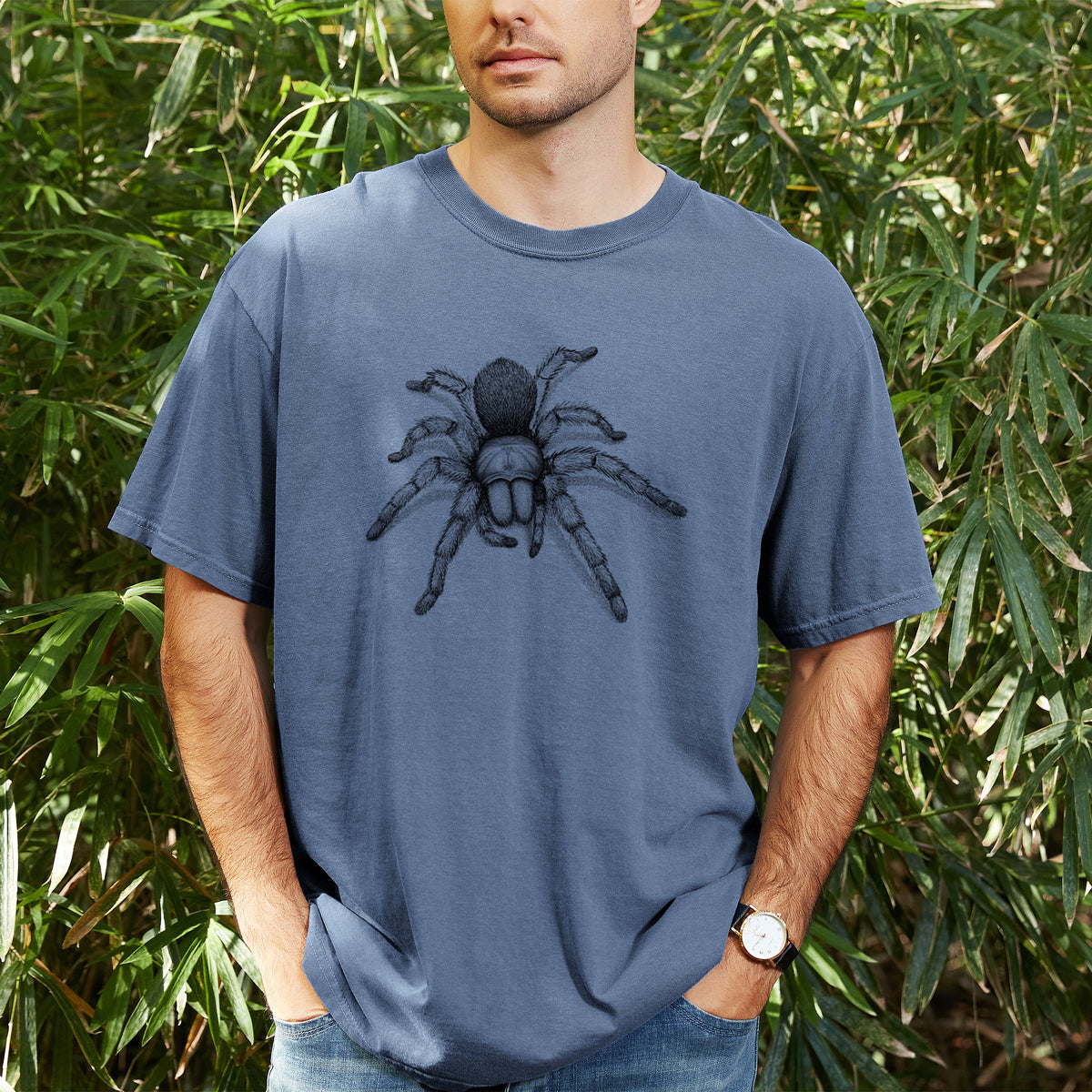 Man wearing a Comfort Colors t-shirt printed with a detailed black ink illustration of a desert blonde tarantula, outdoors.