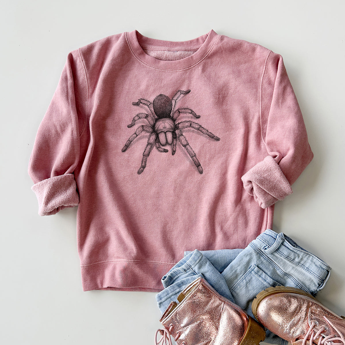 Youth crewneck sweatshirt printed with a detailed black ink illustration of a desert blonde tarantula, styled flat with jeans and boots.